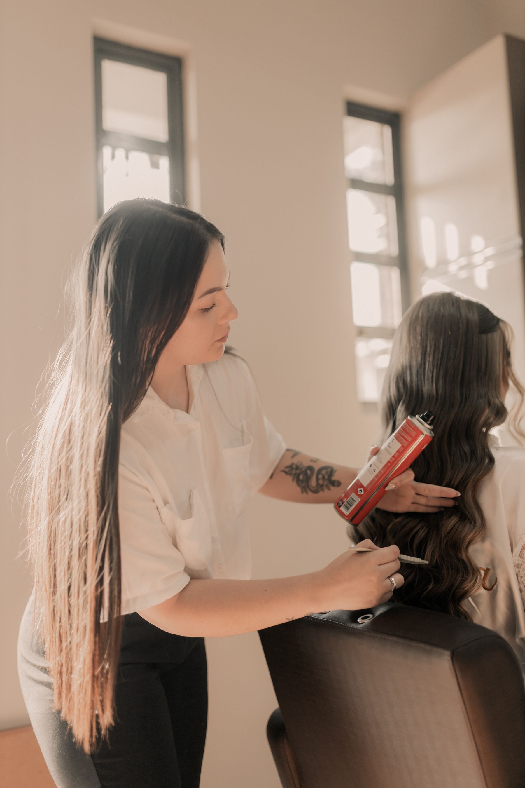 Stylist curling a client's long hair